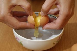 Picture of a brown egg being cracked into a bowl.