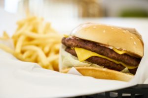 Close up of a cheeseburger with french fries in the background