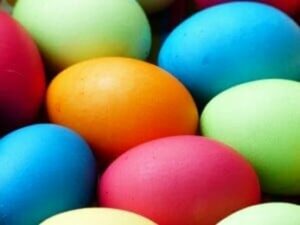 Photo of eggs dyed blue, orange, pink, and green.